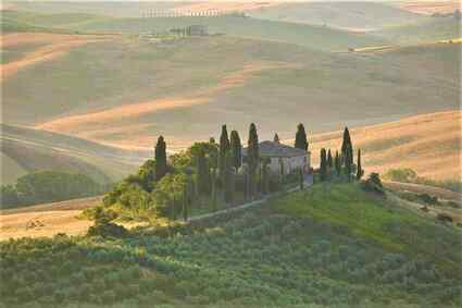 Amazing Tuscan countryside landscape with rolling hills, cypress tree, wineries, and blue sky 