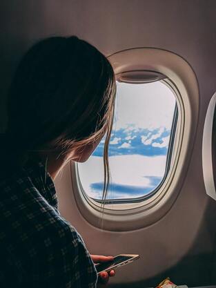 Girl flying on an airplane and looking through the window