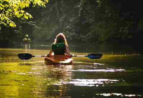 A young woman is canoeing on the river on a sunny day in Costa Rica. 