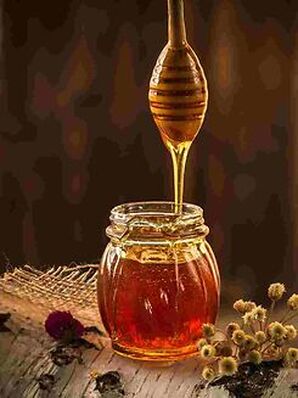 Honey dripping into a glass jar from a special wooden spoon
